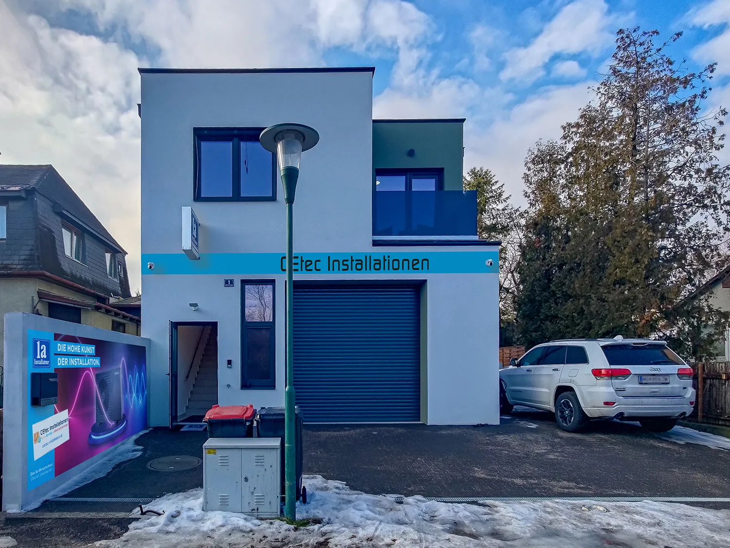 Firmenhaus mit blauem Band und dem Schriftzug CEtec Installationen, davor ein geparktes Auto